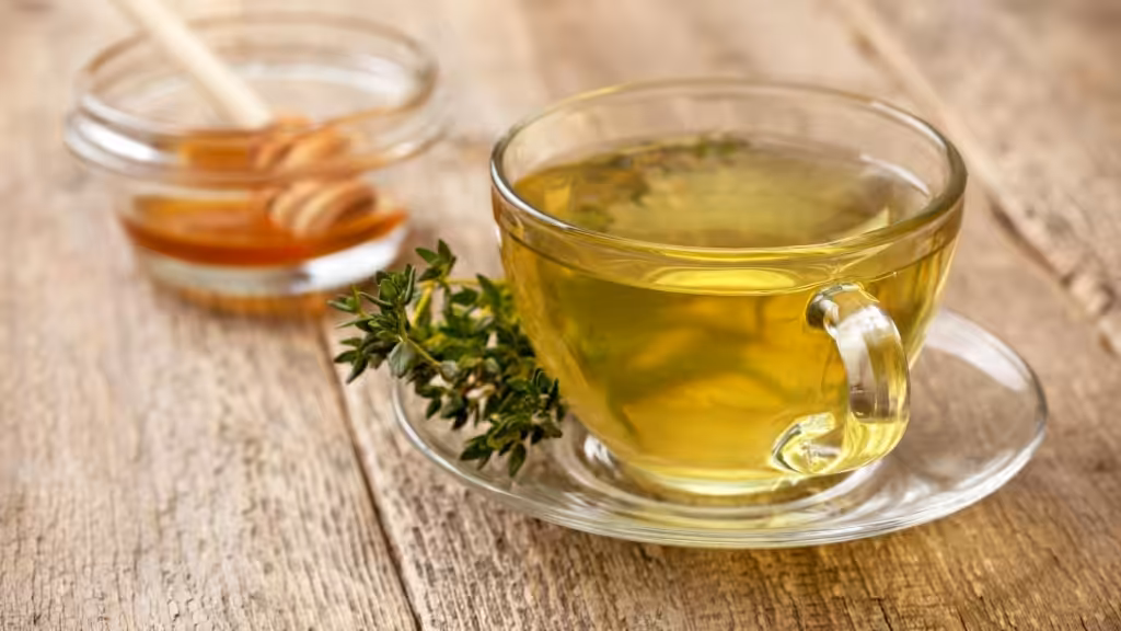 Cup of thyme tea with honey on wooden table