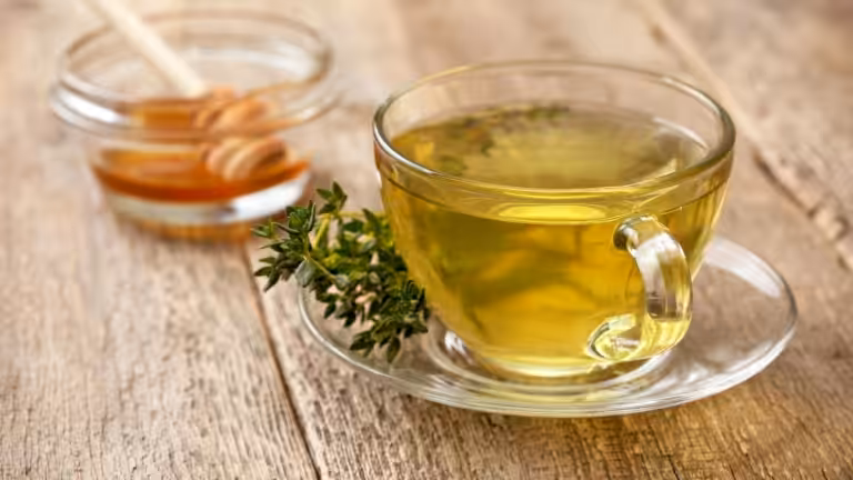 Cup of thyme tea with honey on wooden table