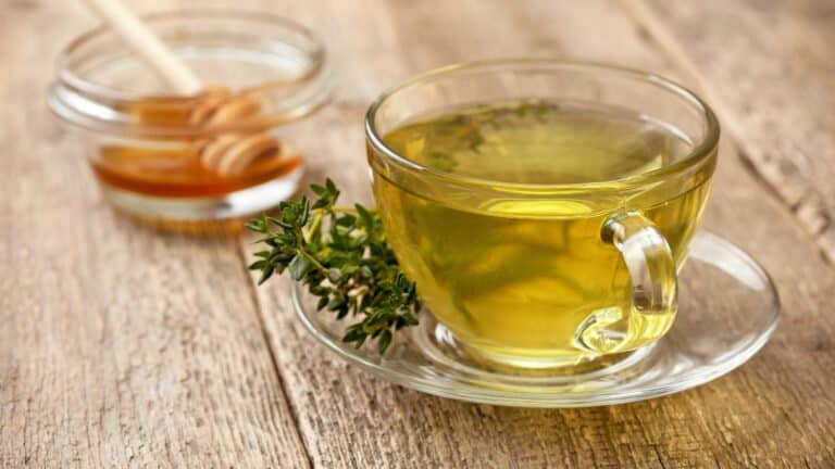 Tasse de thé au thym avec du miel sur table en bois