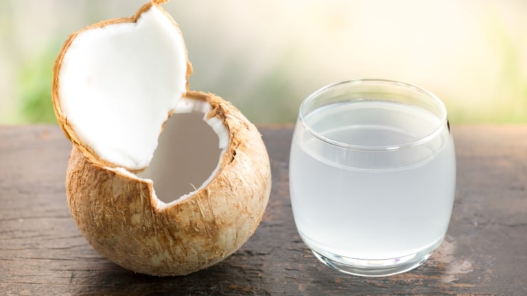 Open coconut with a glass of coconut water