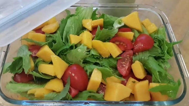 Glasschüssel mit Salat mit Mango und Tomate